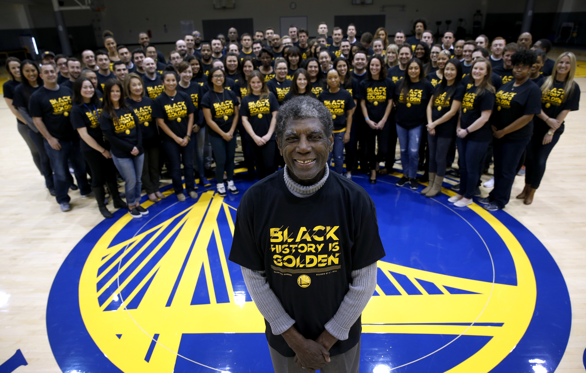 Golden State Warriors legend Alvin Attles joins front office employees to wear a T-shirt designed by Andre Iguodala in honor of Black History Month at the team's headquarters in Oakland, Calif. on Friday, Feb. 19, 2016